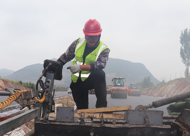 4、油層施工隊(duì)長朱紹濤根據(jù)現(xiàn)場實(shí)際微調(diào)攤鋪機(jī)控制攤鋪質(zhì)量_副本